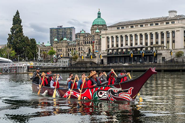 Explore Songhees of the Songhees Nation canoeing past Victoria, BC's iconic Legislature